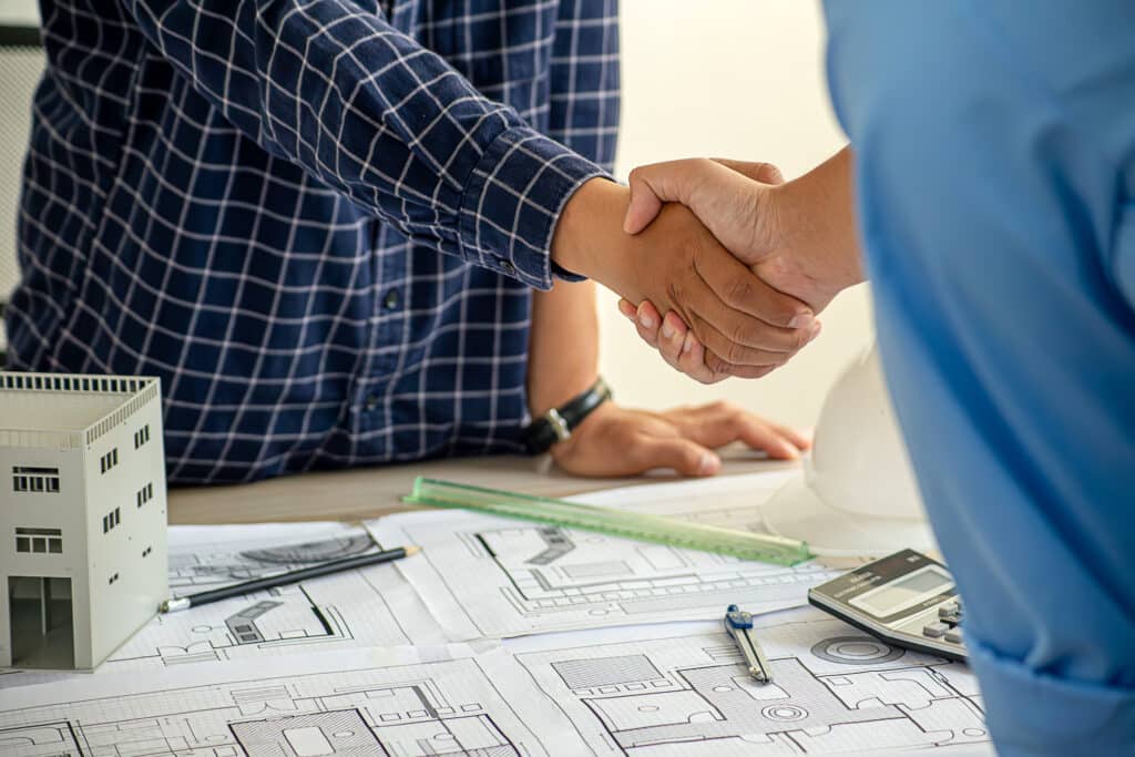 Architect and engineer construction workers shaking hands after successful collaboration.